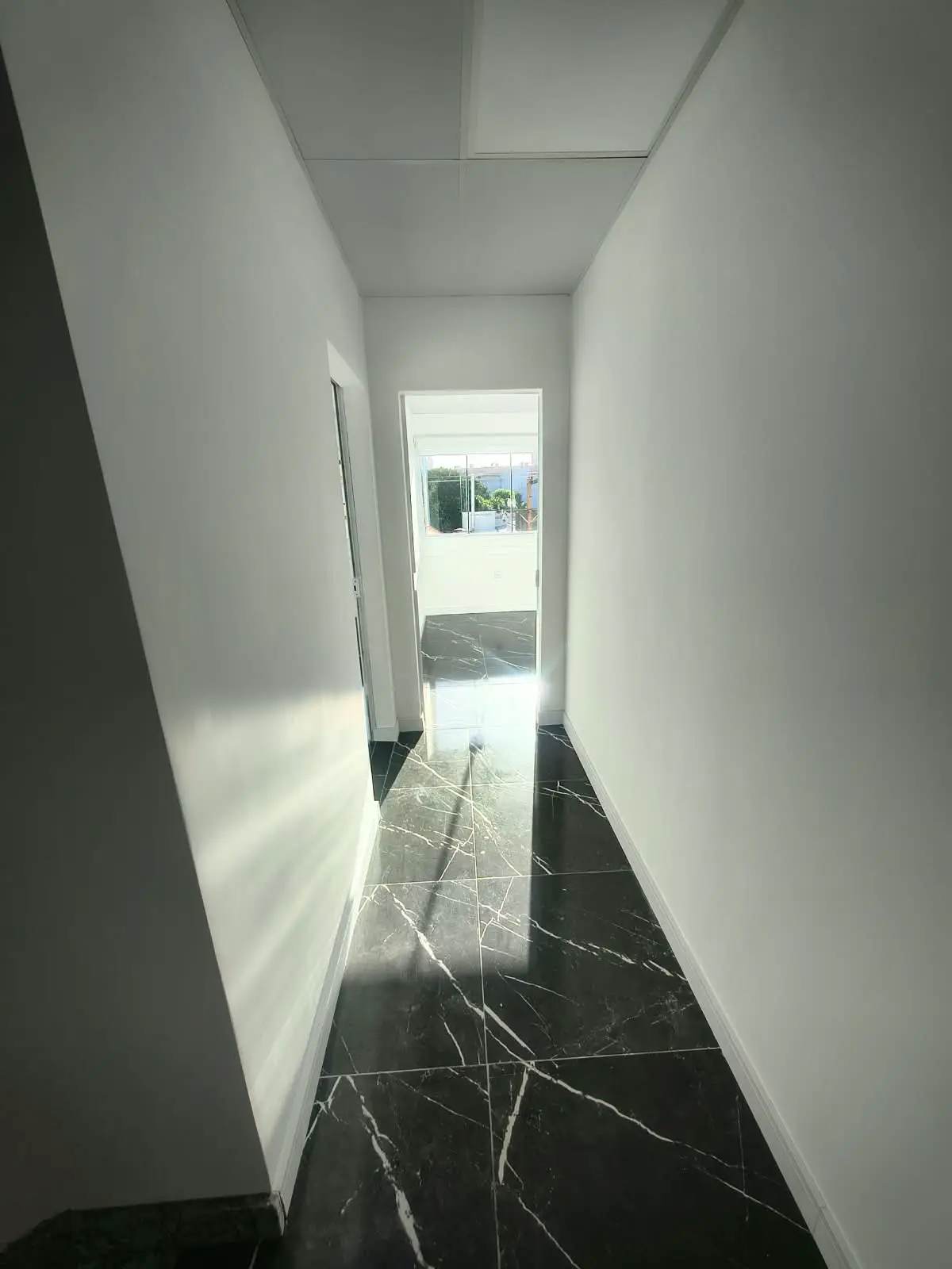 Corredor de acesso com piso em porcelanato preto